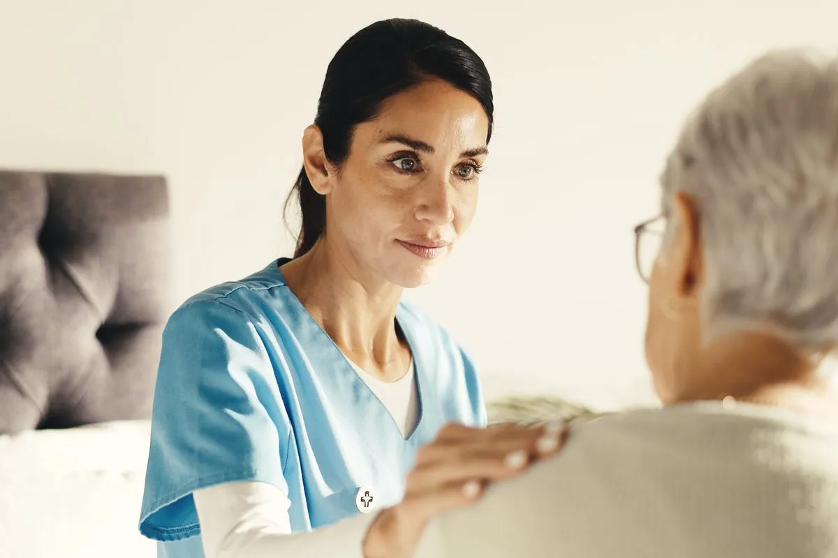 A carer with her hand on an older woman's shoulder