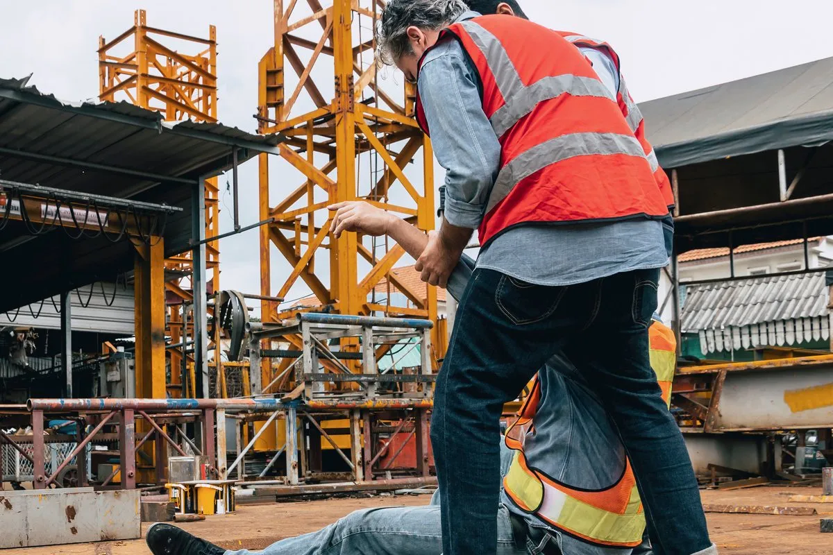A first aider checking on an injured worker on a construction site