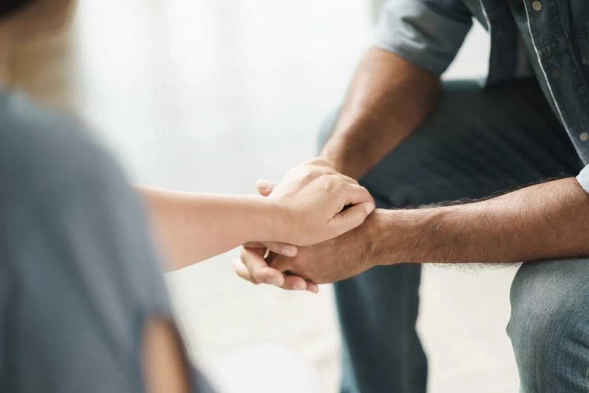 Two people holding hands in support